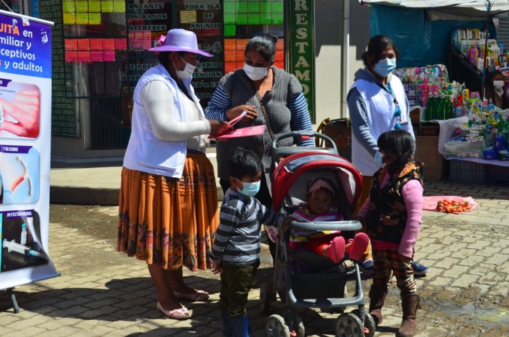 Lucy Quispe Beltran promotora de salud brindando información a la población sobre métodos anticonceptivos y planificación familiar en Feria popular en la ciudad de El Alto. 