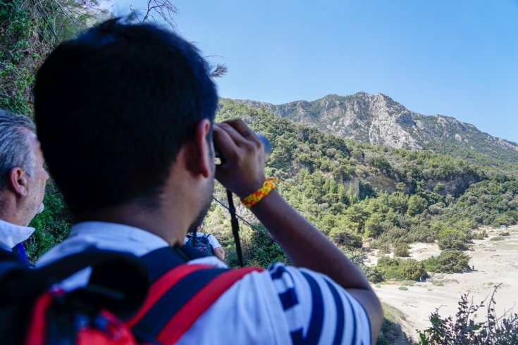 Un miembro de MSF busca en el bosque con los prismáticos durante una respuesta médica de emergencia en la isla de Samos, Grecia.