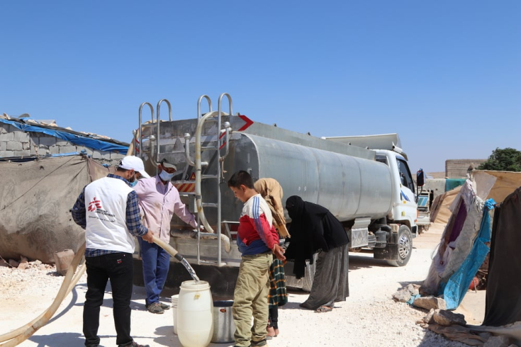 Personas desplazadallenan sus garrafas con agua limpia proporcionada por MSF en un campo en el noroeste de Siria.
