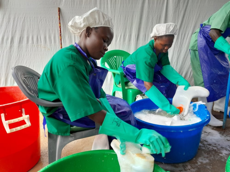 Las higienistas lavan las botas con cloro para evitar la propagación del Ébola. Centro de tratamiento de Mubende