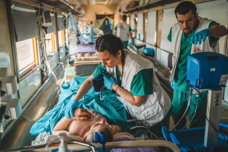 El equipo médico dentro de la unidad de cuidados intensivos (UCI) del tren médico de MSF supervisa y estabiliza a un paciente gravemente herido de guerra durante el viaje desde Pokrovsk, en el este de Ucrania, hasta Lviv, en el oeste de Ucrania.
