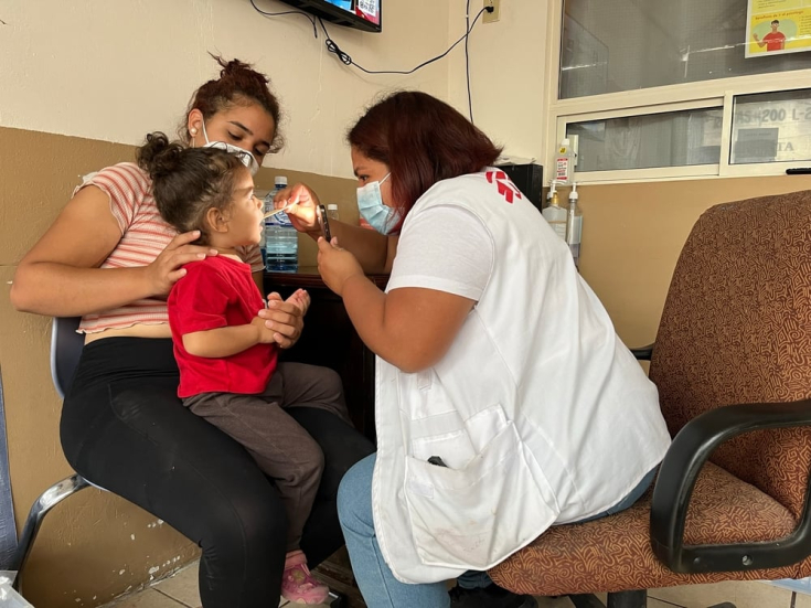 Una enfermera asiste a una niña con afecciones respiratorias leves. Ella y su madre son migrantes atrapadas en el norte de México.