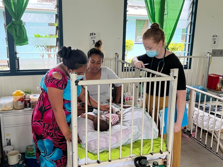 La doctora Meritima, pediatra residente de Kiribati, examina a Nei Aam, de cinco meses, ingresado con bronquiolitis en el Hospital Central Tungaru de Tarawa. También está presente la madre del bebé, Bwaurina Tekiaa, y la pediatra de MSF, Joanne Clarke.